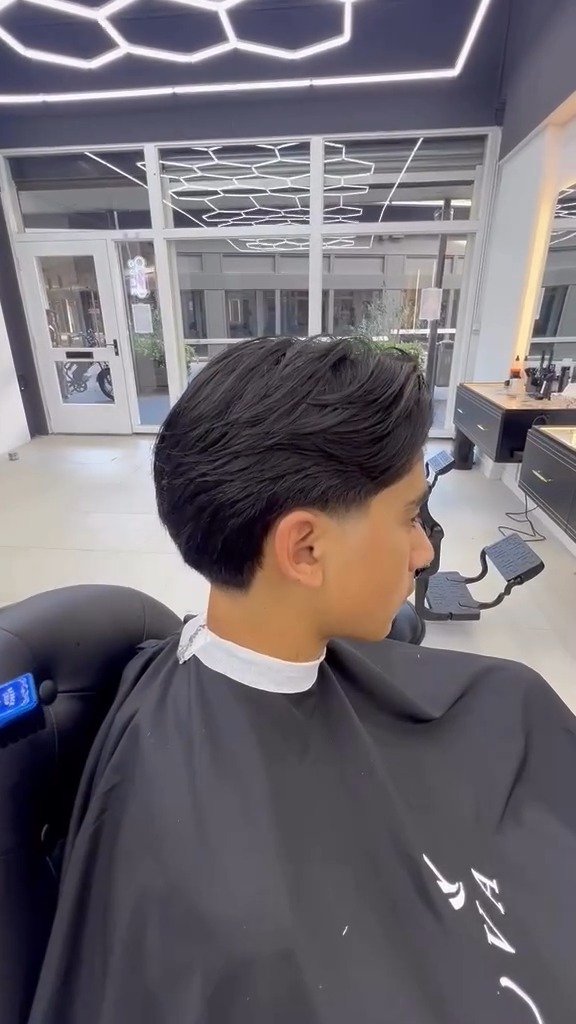 Zijaanzicht van een klant met een donkere textured crop in een NOVA-kapmantel