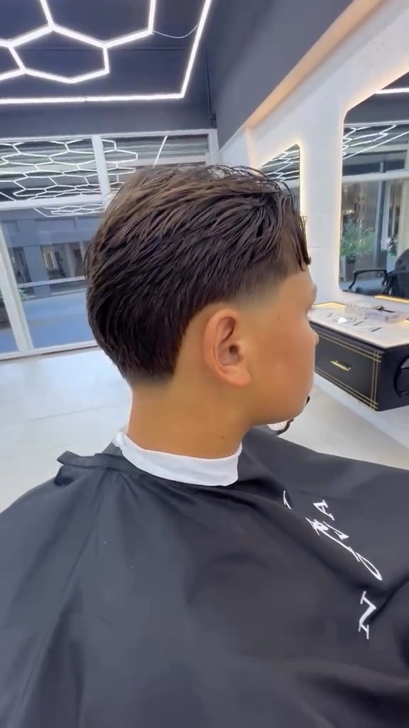Klant met een mid fade en getextureerd haar, van opzij gezien